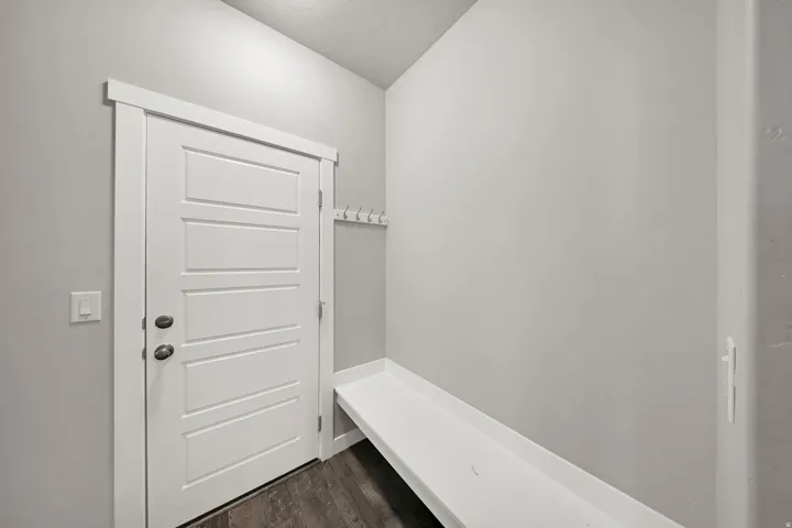 White paneled door with dark hardware, built-in storage bench, and wood-finish flooring
