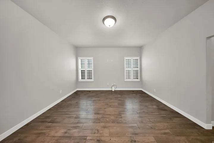 Hardwood-finish flooring, plantation shutters, flush mount lighting, and neutral wall tones