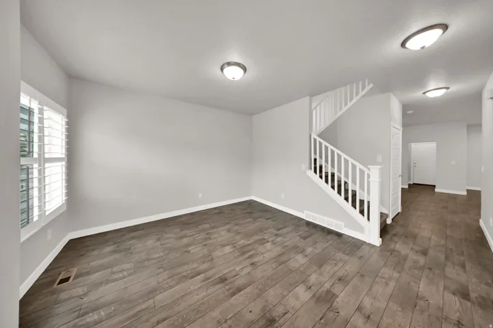 Wood-finish flooring, white plantation shutters, staircase with white railings, and flush-mount lighting fixtures