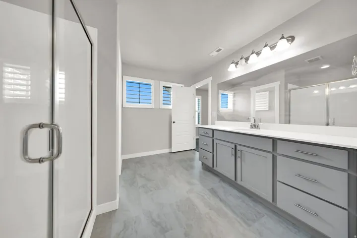 Spacious vanity with light gray cabinetry, white countertop, and dual sinks