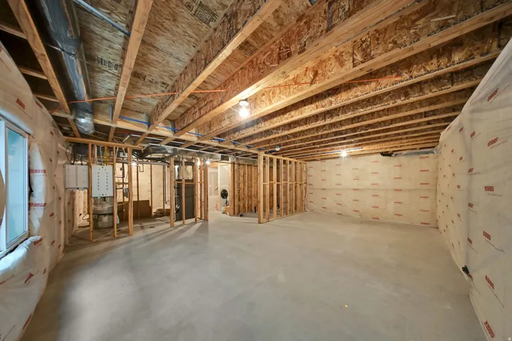 Unfinished basement with exposed ceiling joists, concrete flooring, framed wall sections, and insulation-wrapped exterior walls