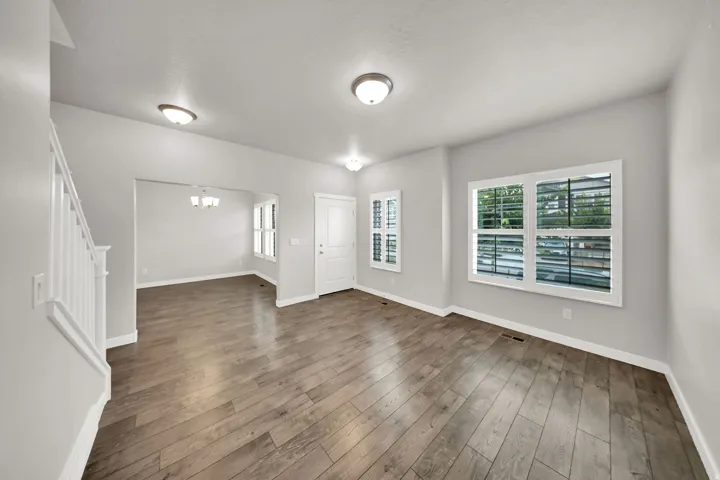 Formal Living Room Wood-finish flooring throughout, white interior trim, white staircase balusters, and a front entry door with side shutters