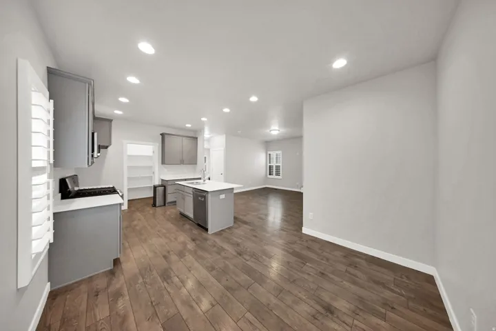 Open-concept kitchen and living area featuring wood-finish flooring, recessed lighting, and white walls