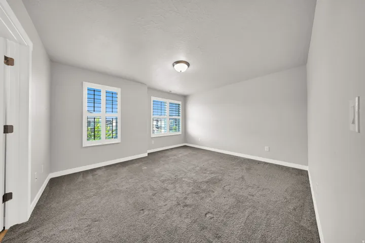 Primary Bedroom Neutral wall paint, two windows with white plantation shutters, and recessed ceiling lighting