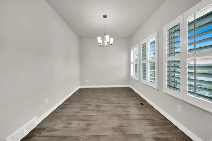 Formal Dining Area Wood-finish flooring with a neutral wall color, recessed lighting, and a multi-bulb chandelier