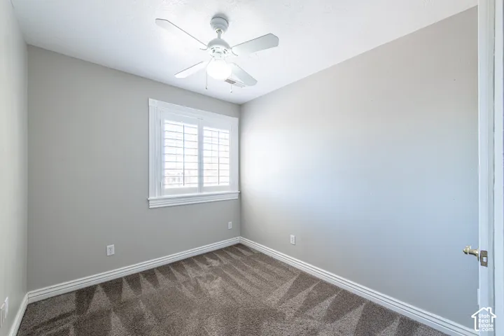 Window with plantation shutters, ceiling fan with integrated lighting, neutral wall paint, and plush carpet