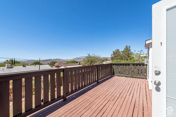 Expansive outdoor deck with wood railing, offering broad views of distant hills and surrounding properties