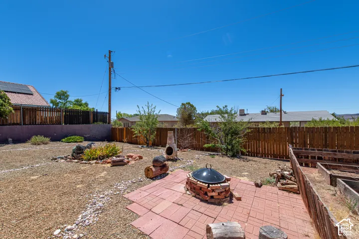 Expansive backyard featuring a brick paver patio, a built-in brick fire pit, and a wooden privacy fence