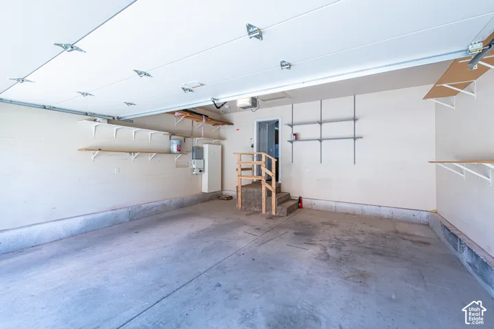 Concrete flooring, built-in shelving, wall-mounted water heater, and interior access door