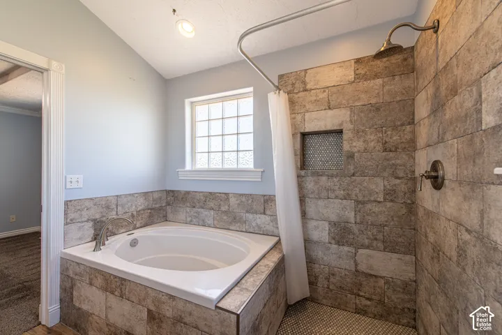Corner soaking tub with a tiled surround, adjacent to a shower with stone-finish wall tile