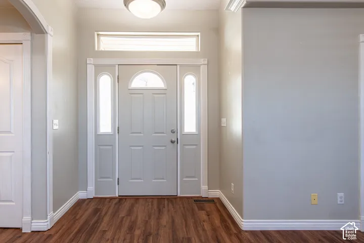 Entryway featuring a panel door with an arched transom, sidelights, and wood-finish flooring
