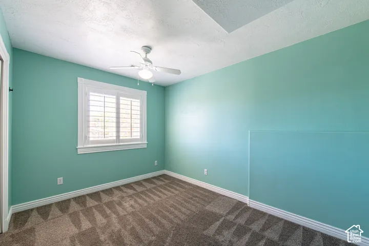 Room featuring a ceiling fan, white window shutters, and patterned carpet