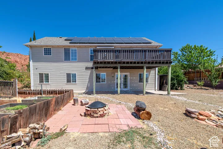 Rear exterior with siding, upper-level deck, ground-level patio, and rooftop solar panels