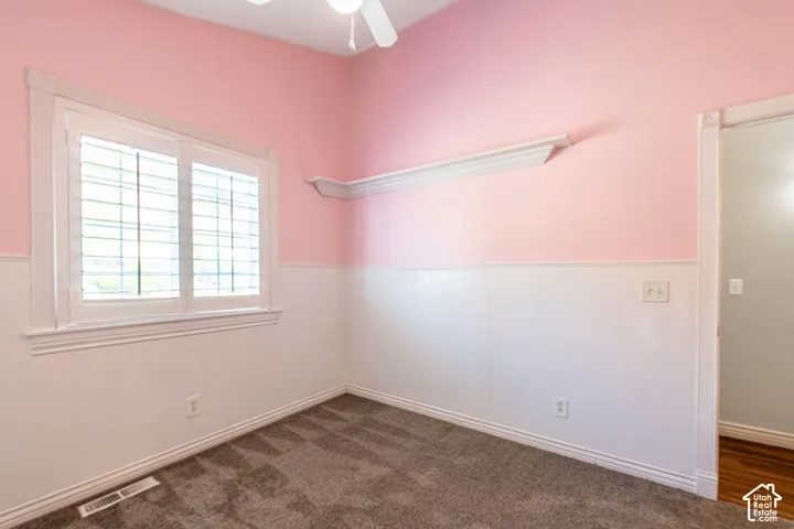 Carpeted flooring with white wainscoting and pink walls