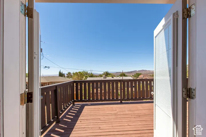 Expansive wood-plank deck with a dark wood railing, accessed through double French doors