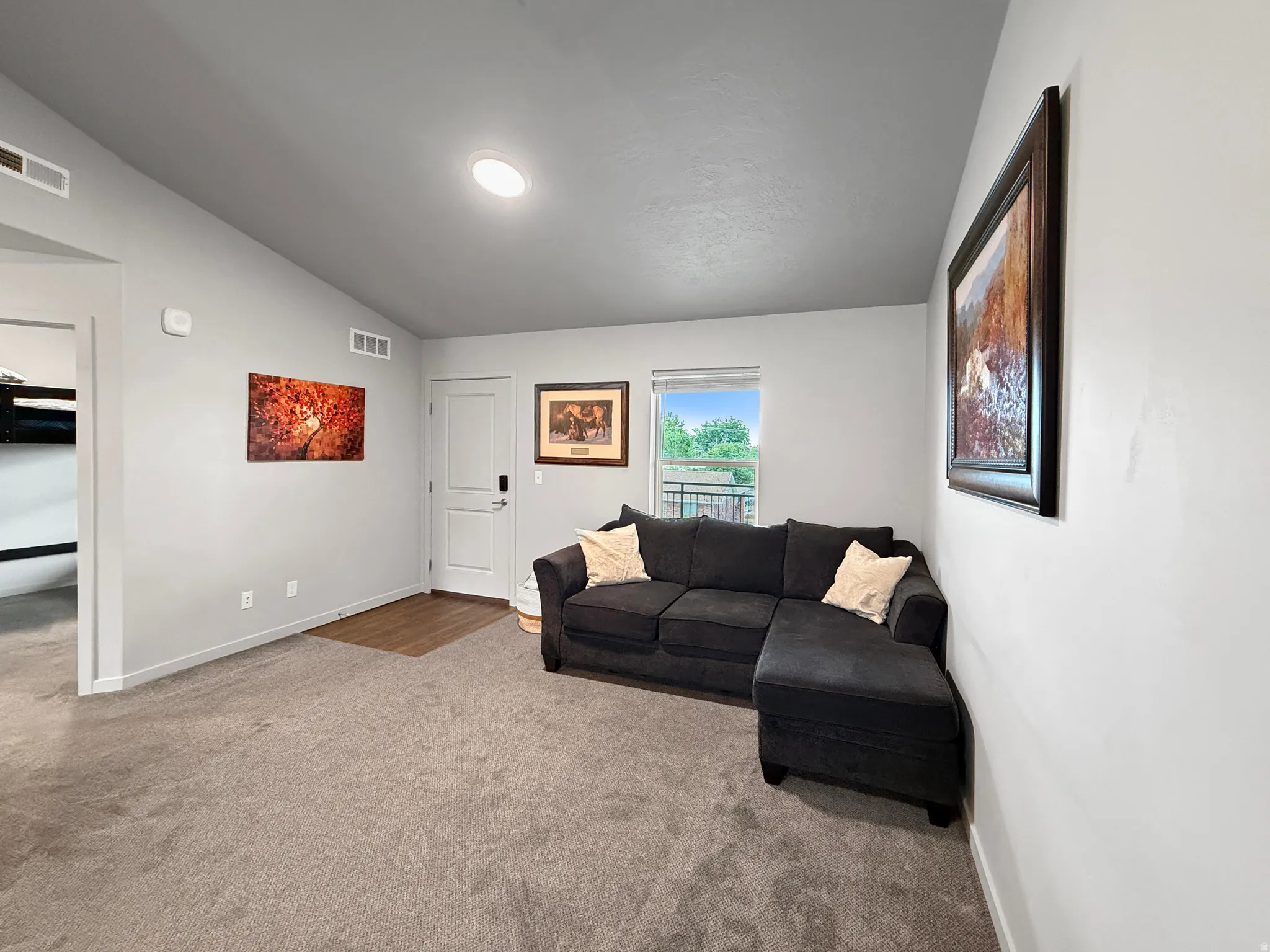 Carpeted living area with light gray walls and a recessed ceiling light