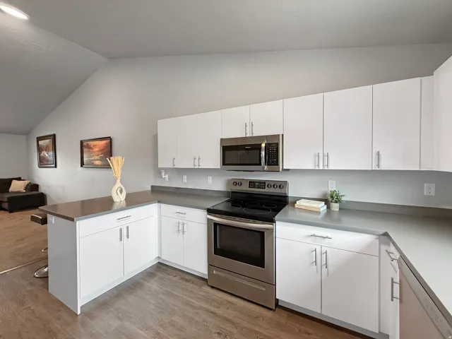Kitchen featuring white cabinetry, stainless steel appliances, grey countertops, and wood-finish flooring