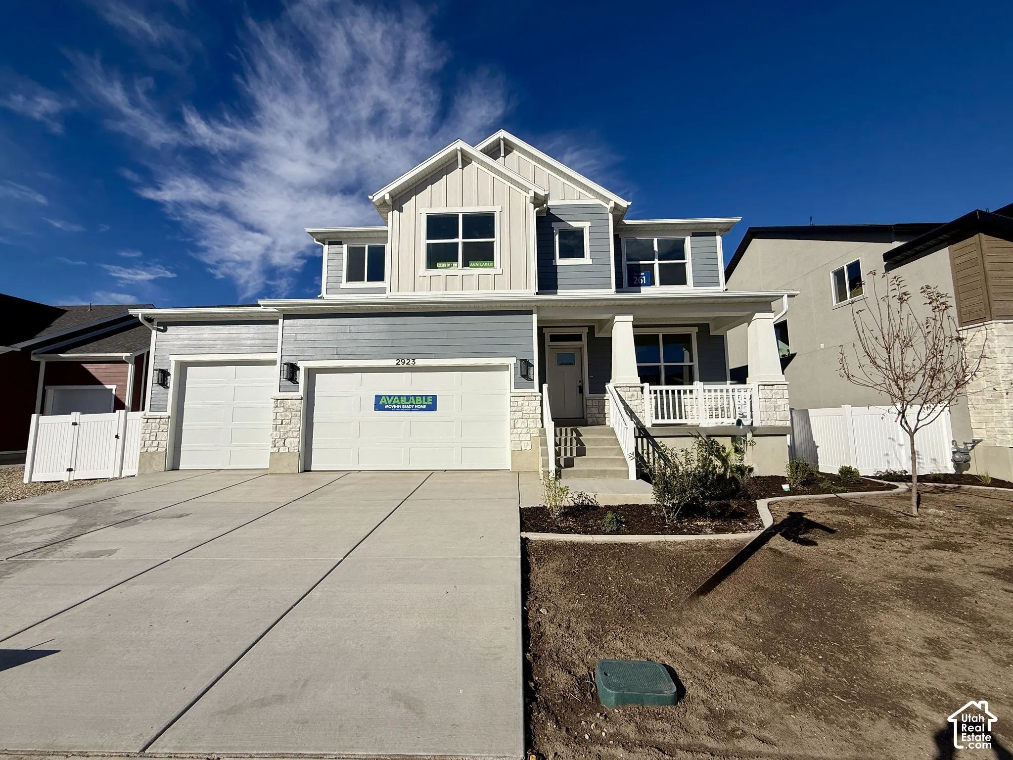 Two-story exterior featuring fiber cement siding, stone veneer accents, multi-gabled roofline, covered porch with columns, and a three-car garage