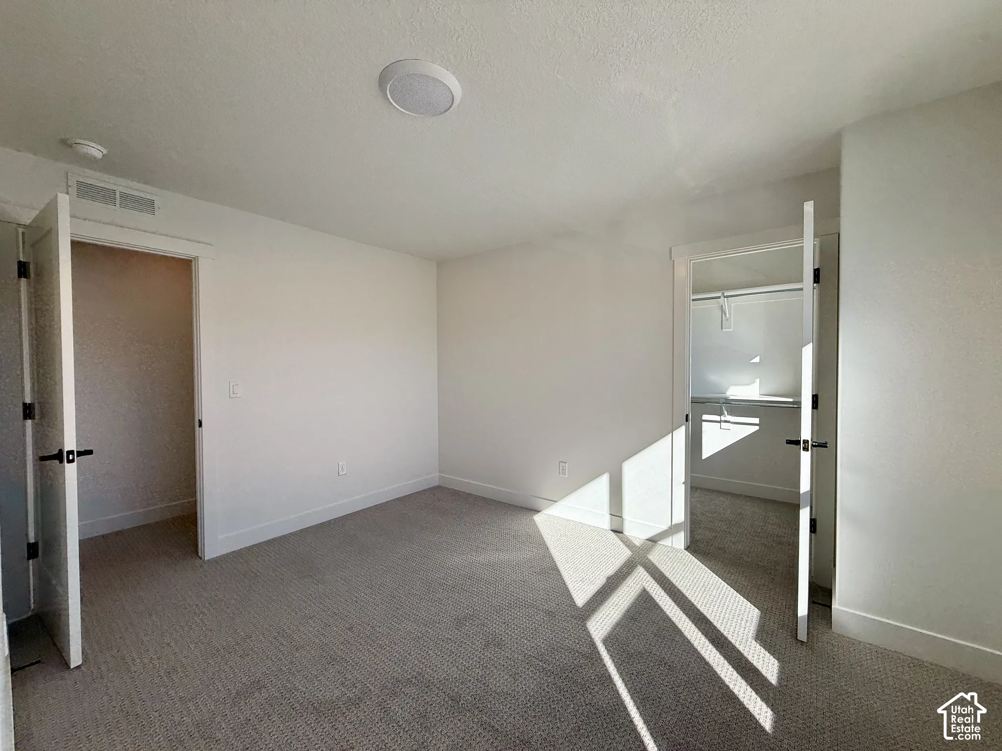 Neutral-toned carpeting, two doorways with shaker-style doors, and integrated closet storage