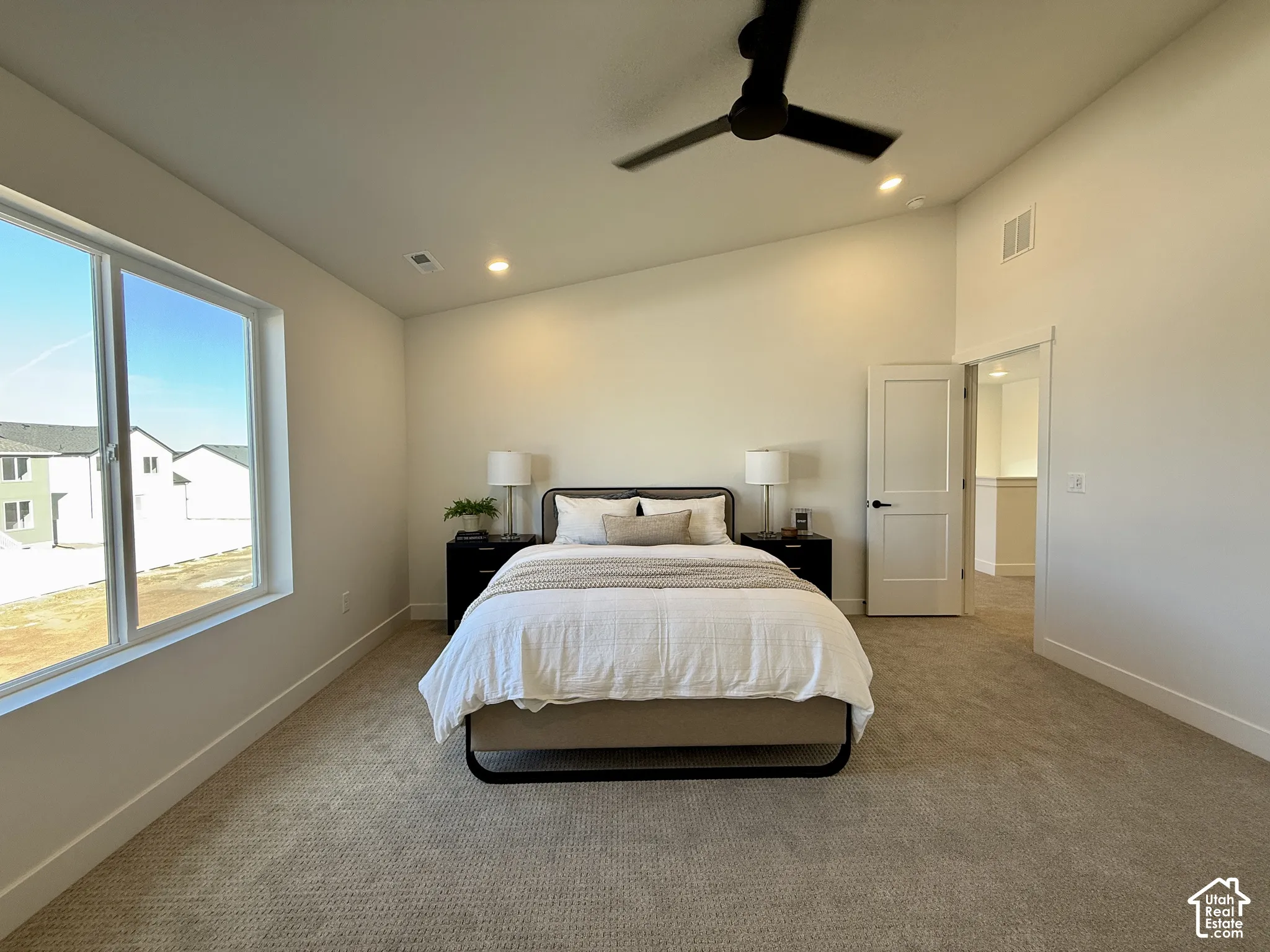 High-ceilinged room featuring neutral carpeting, a black matte ceiling fan, recessed lighting, and a large multi-pane window