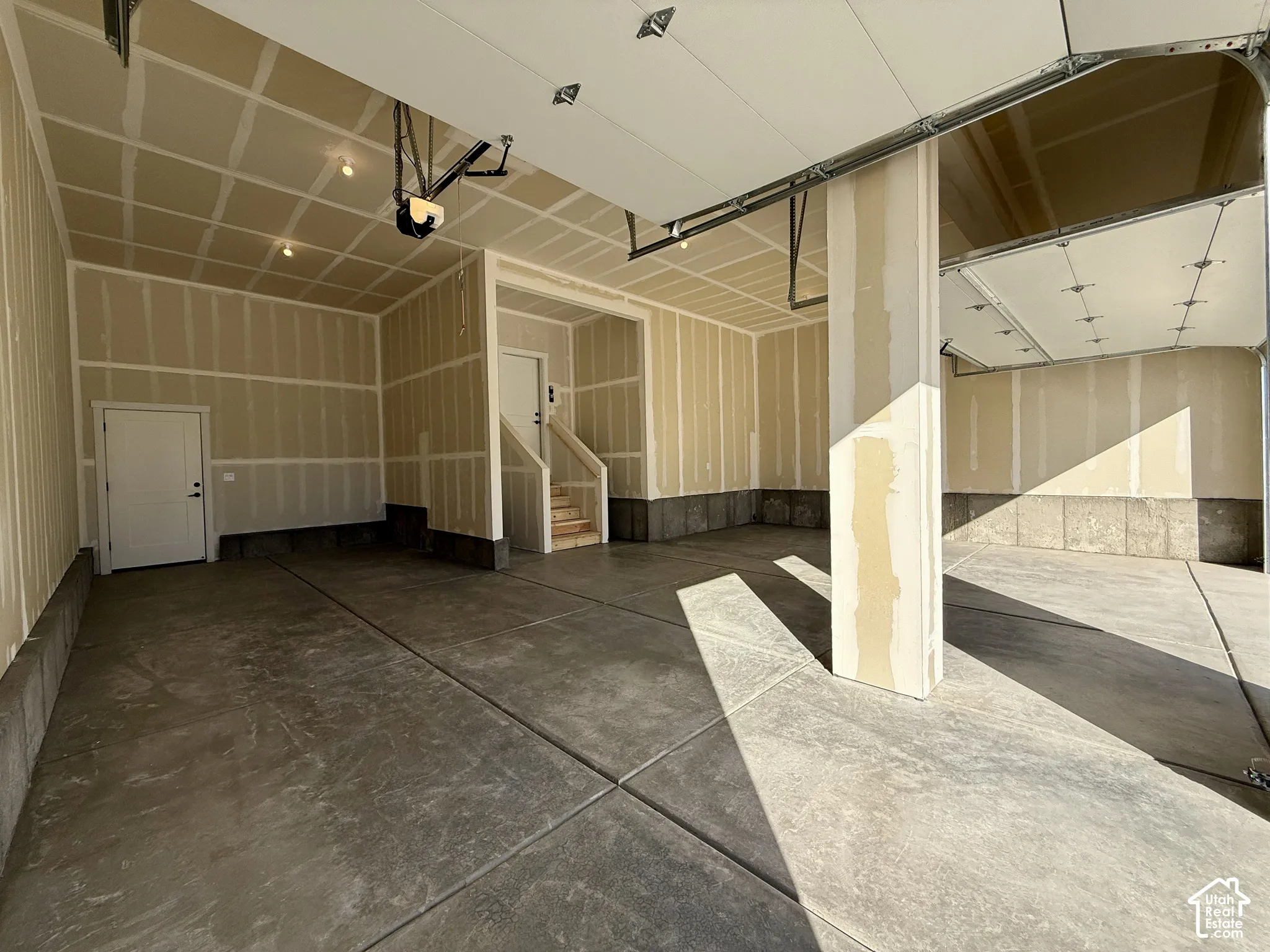 Multi-vehicle garage featuring a concrete floor, finished drywall, recessed lighting, and an internal staircase