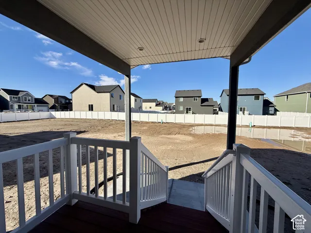 Covered porch featuring a wood-finish deck, white railing, and a vinyl privacy fence