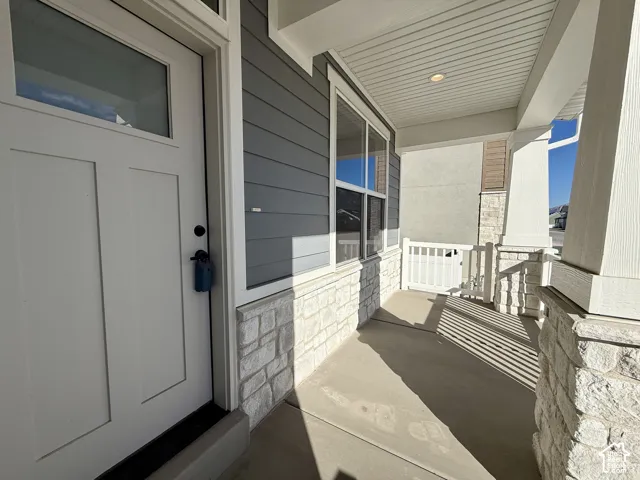 Covered entryway featuring horizontal lap siding, stone veneer base, white-framed glass paneled door, and recessed lighting
