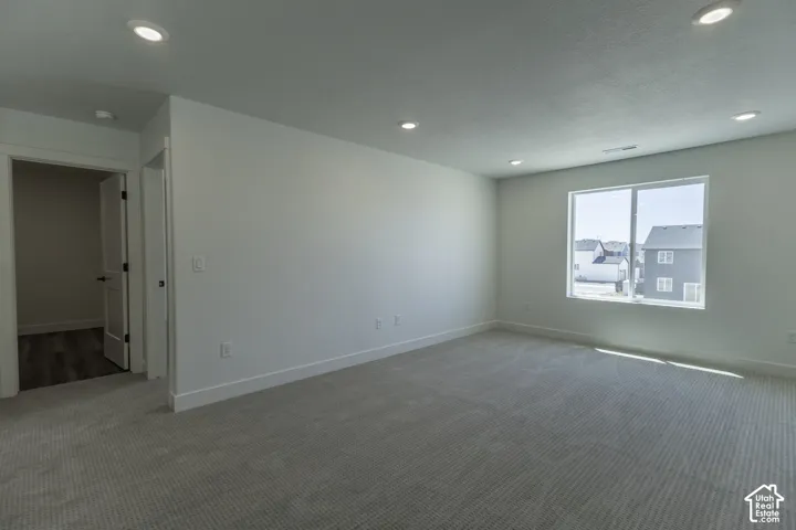 Spacious room with recessed lighting, light-toned carpeting, a large window, and white trim