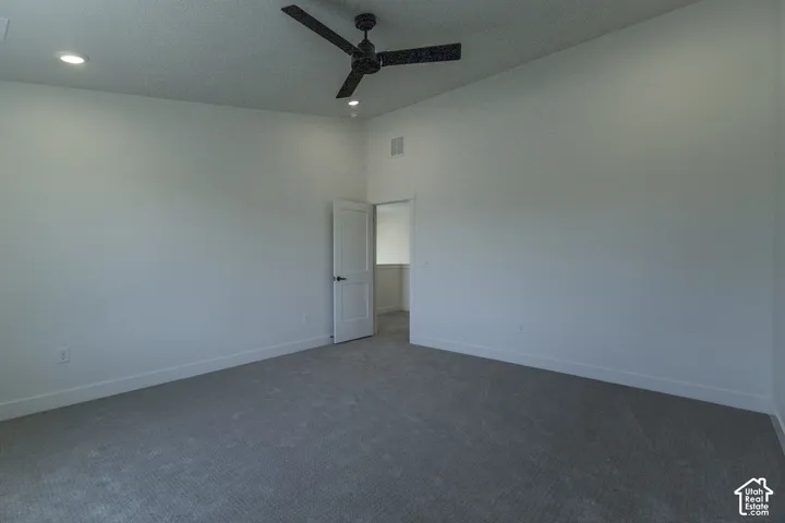Spacious room featuring neutral carpeting, recessed lighting, a modern ceiling fan, and a white interior door