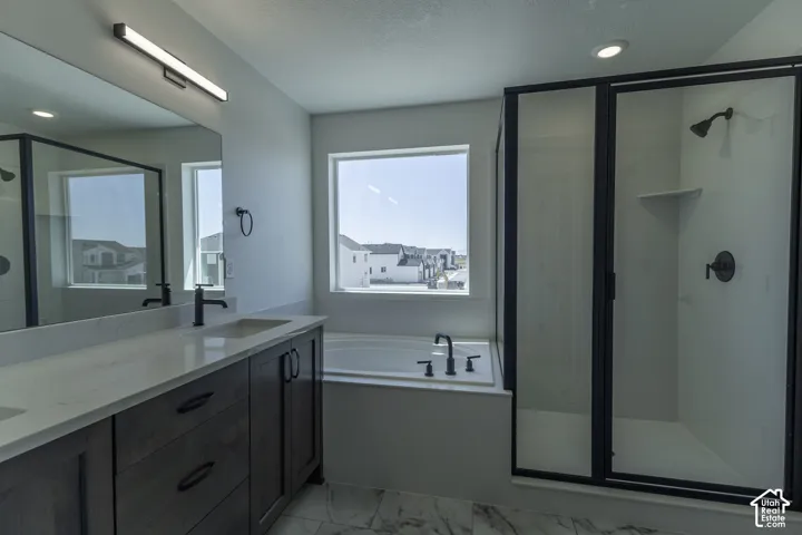Dual sink vanity with dark wood-finish cabinetry, a large built-in bathtub, a walk-in shower with a glass enclosure, and modern matte black fixtures
