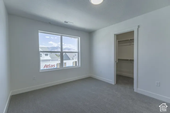 Recessed lighting, light gray carpeting, crisp white walls, white trim, and a built-in closet with shelving