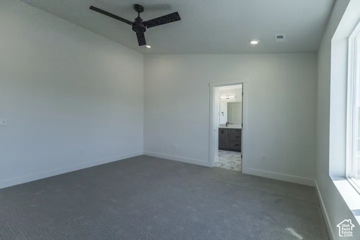 Spacious room with plush carpeting, a ceiling fan, recessed lighting, and a large window