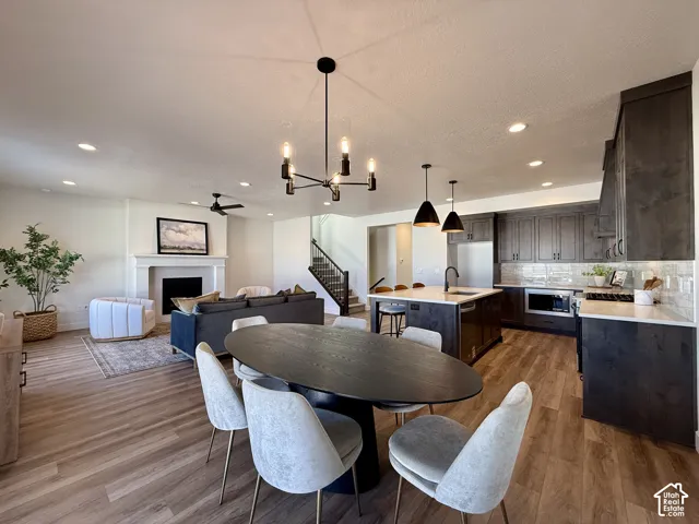 Open-concept interior featuring wood-finish flooring, a kitchen island with stone-surface countertops, dark stained wood cabinetry, and a fireplace with a decorative mantel