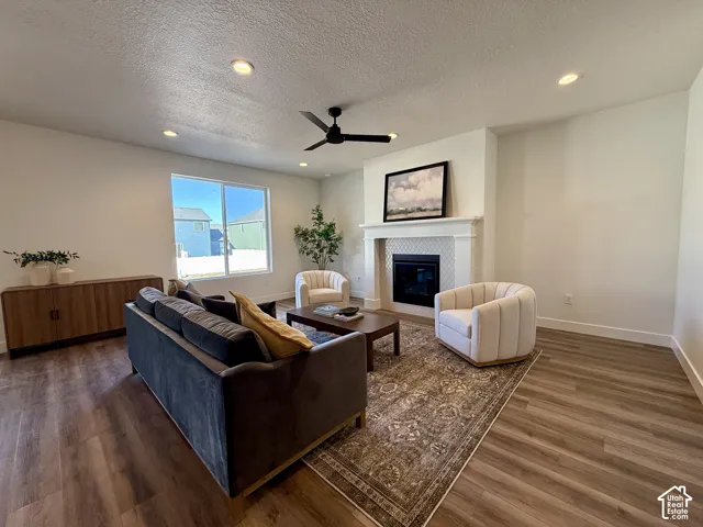 Fireplace with an ornate mantel and tiled surround, wood-finish flooring, recessed lighting, and a modern ceiling fan