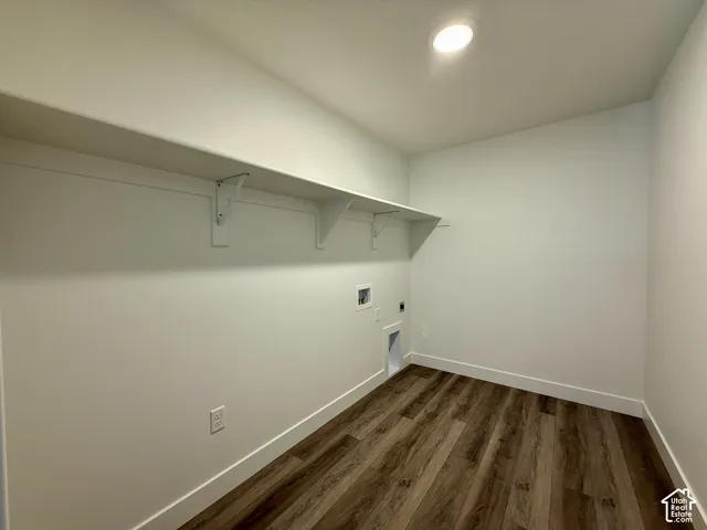 Utility space featuring wood-finish flooring, a full-length wall-mounted shelf with support brackets, and recessed ceiling lighting