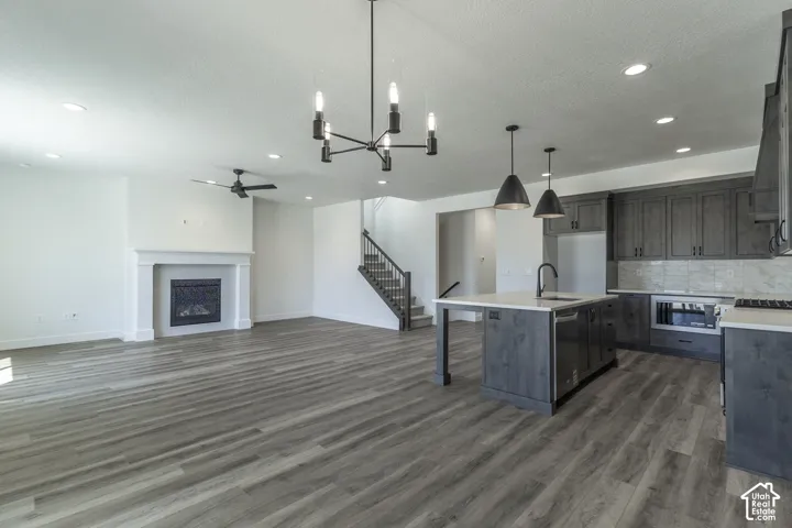Expansive living area featuring wood-finish flooring, a white mantel fireplace, and a contemporary ceiling fan