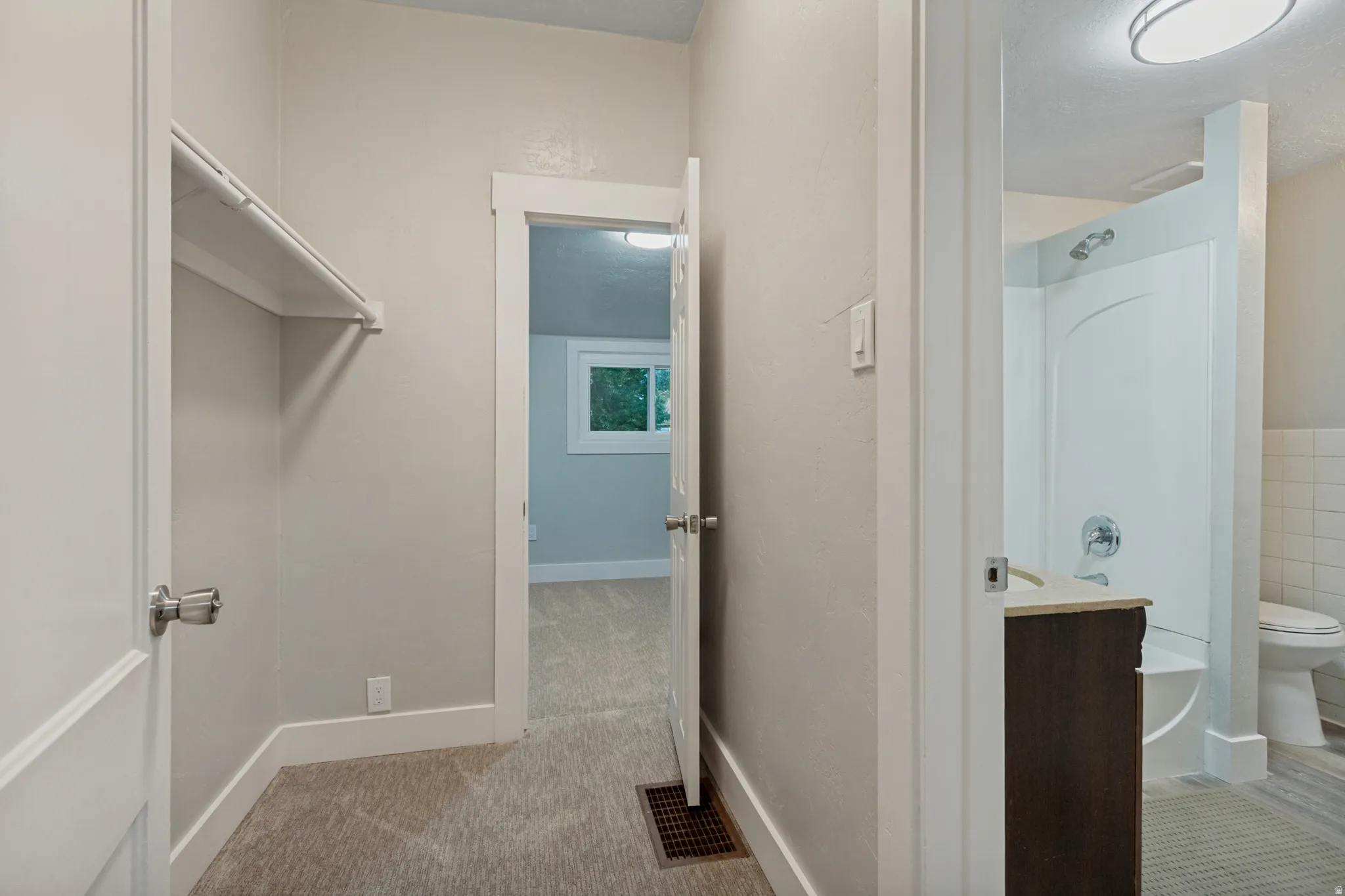 Neutral wall color, white trim, carpeted flooring, built-in closet shelving, and a vanity with a countertop