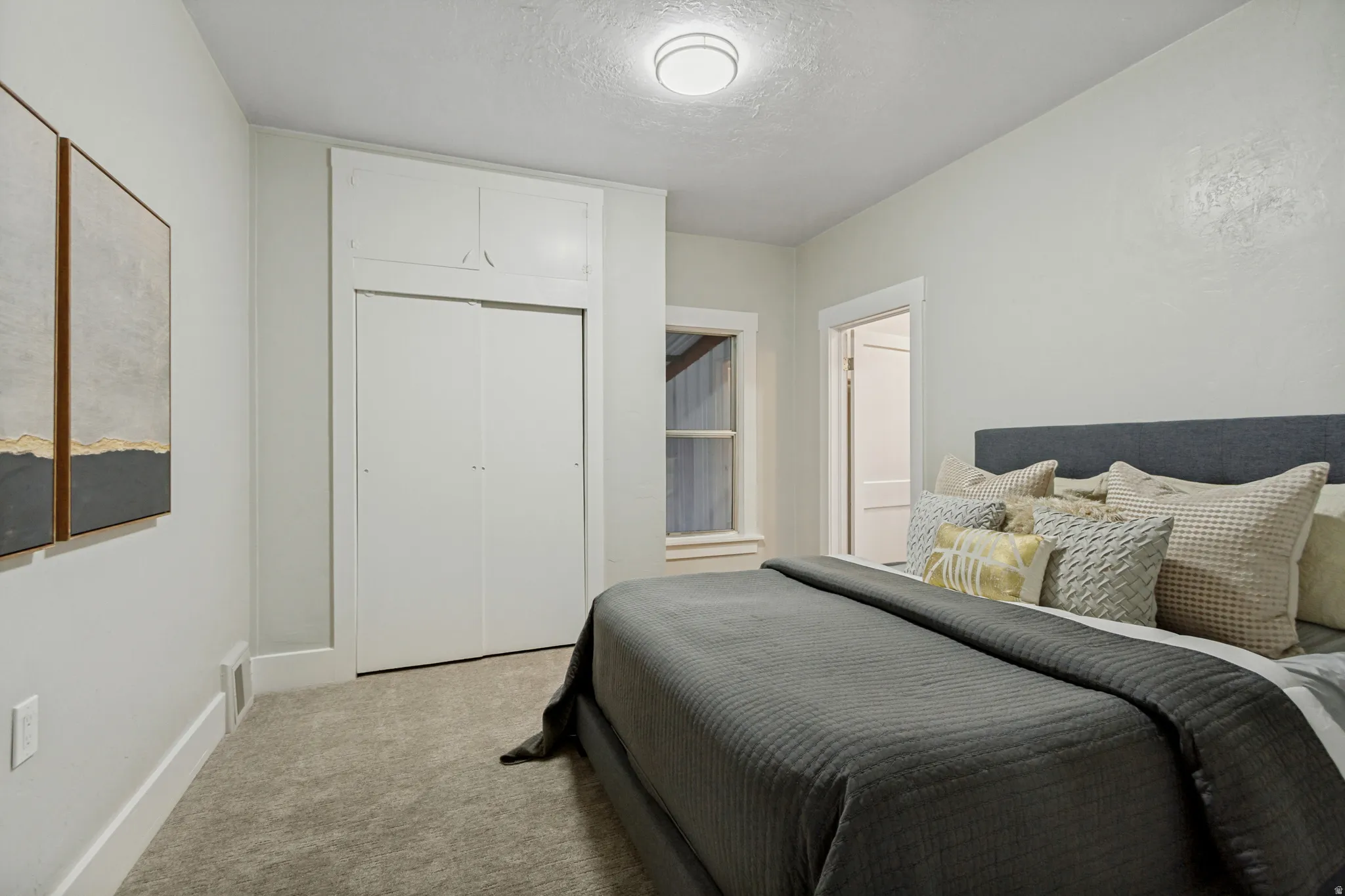 Recessed lighting, light gray carpet, window with white trim, built-in closet with sliding doors, and upper built-in storage