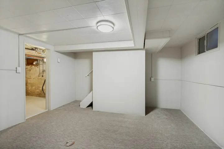 Carpeted flooring, drop ceiling, white panel walls, recessed window, and staircase