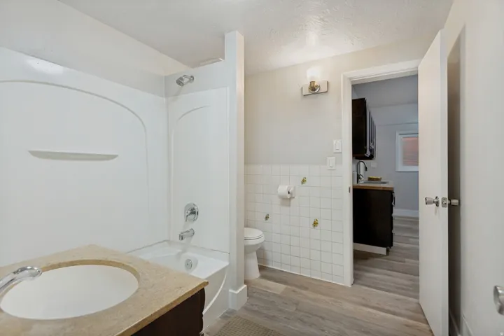 Full bathroom featuring a shower-tub combination, a vanity with an integrated sink, and wood-finish flooring