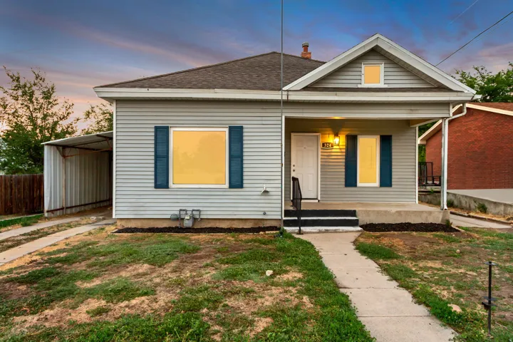 Covered front porch with light fixture, vinyl siding, asphalt shingle roof, and a detached carport