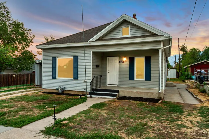 Siding exterior with a covered porch entry, asphalt shingle roof, and a concrete pathway