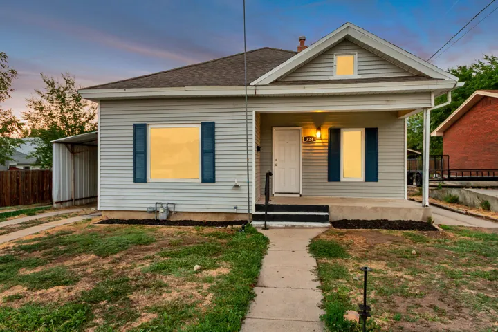 Siding exterior with a covered front porch, prominent dormer, and a paved driveway