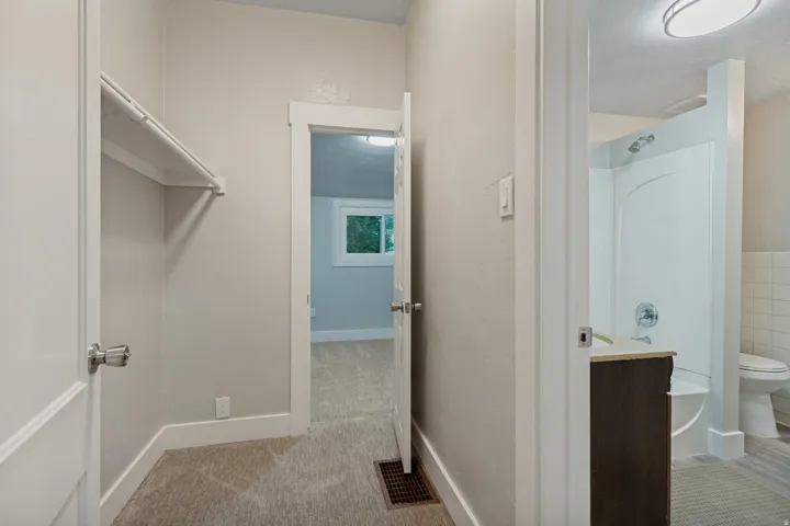 Neutral wall color, white trim, carpeted flooring, built-in closet shelving, and a vanity with a countertop
