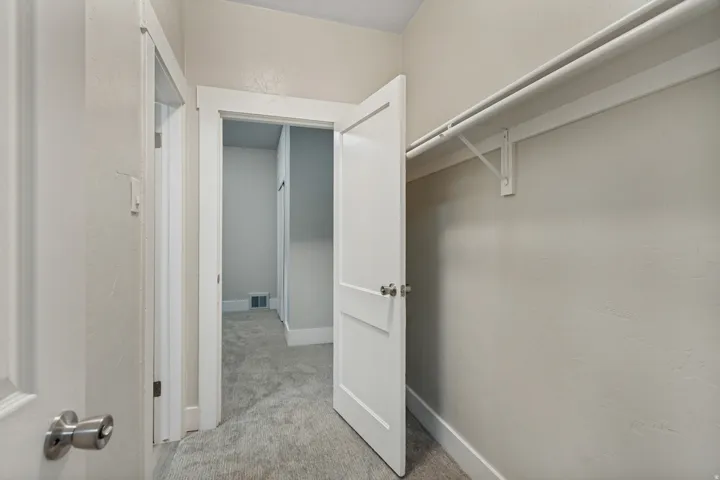 Closet space featuring a built-in shelf and hanging rod, neutral wall color, and white trim