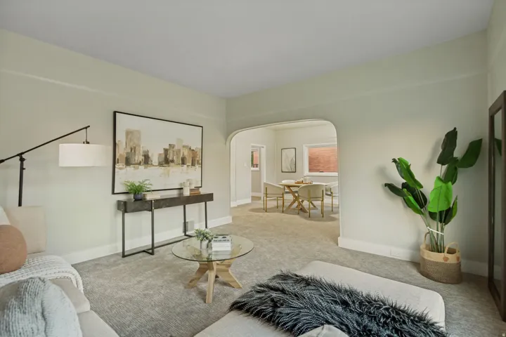 Archway entry to dining space, wall-to-wall carpeting, light wall paint throughout, and natural light from dining area windows