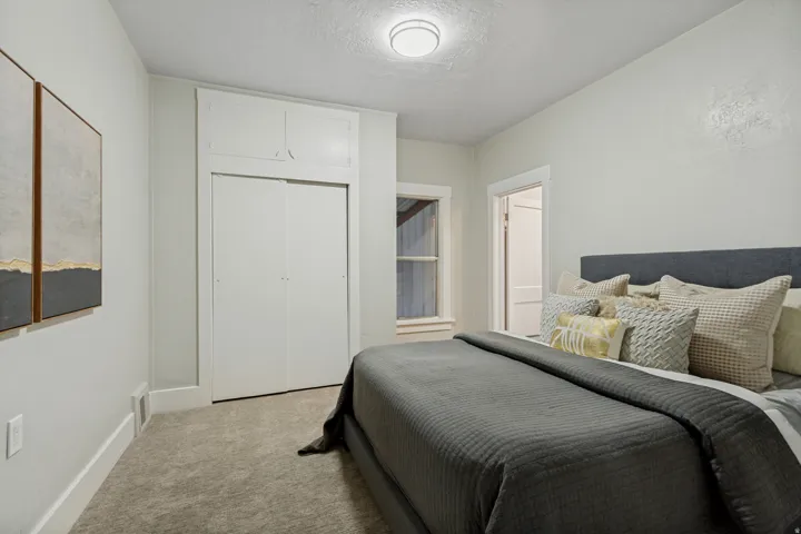 Recessed lighting, light gray carpet, window with white trim, built-in closet with sliding doors, and upper built-in storage
