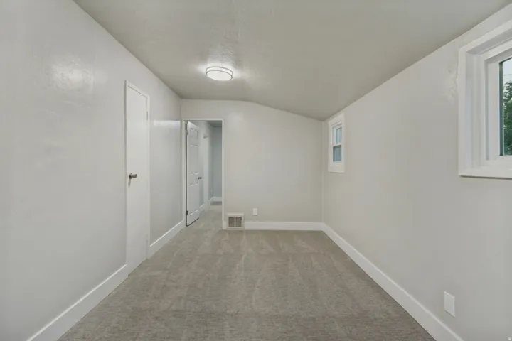 Gray textured carpeting, white trim, white interior doors, and two windows