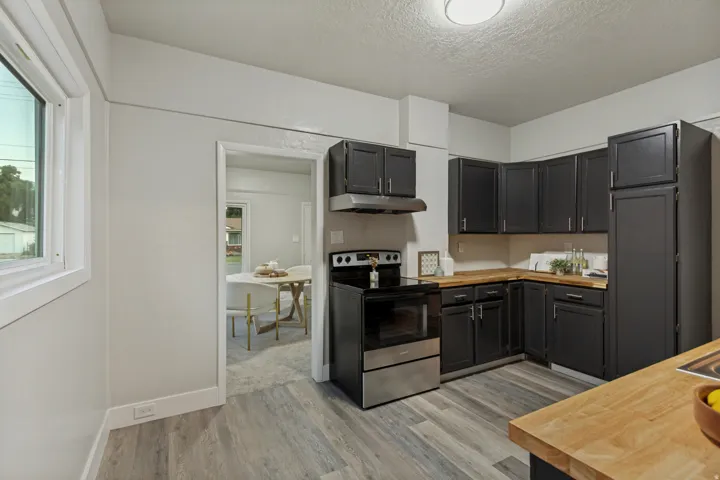 Kitchen featuring wood-finish flooring, dark cabinetry, wood countertops, and stainless steel appliances