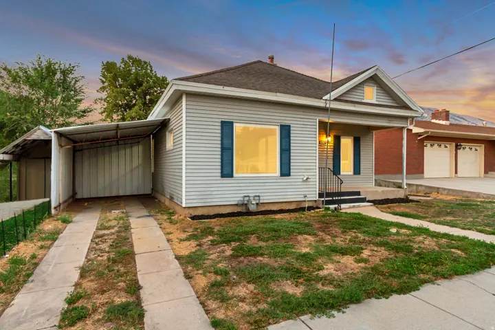 Siding exterior with a covered porch, front entry steps, and a paved driveway leading to a covered carport